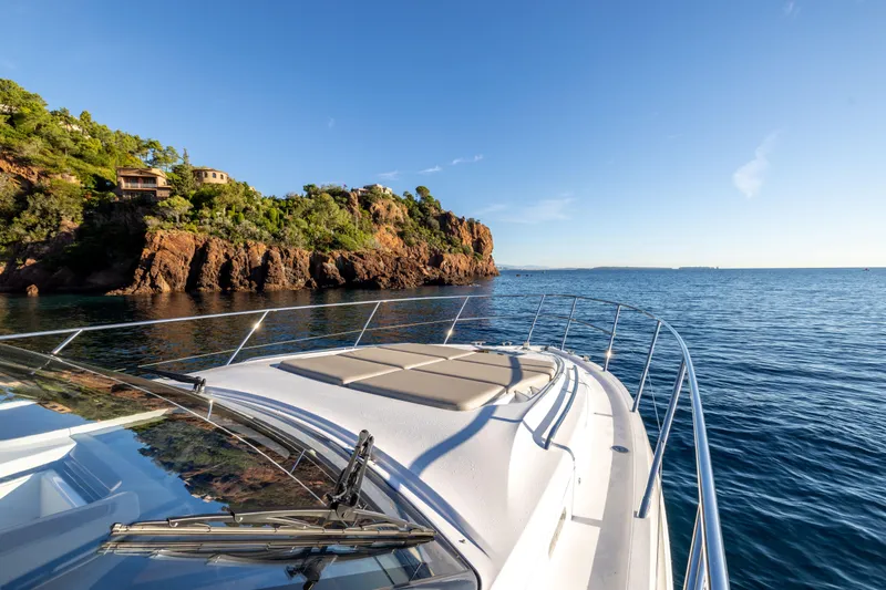 V50 Open Yacht Photos Pics 2026 Princess V50 Open yacht cruising near rocky coastline under clear blue sky.