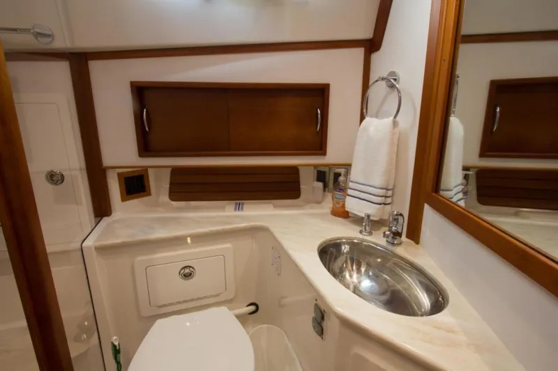 Ohana Yacht Photos Pics 2016 Sabre Flybridge yacht bathroom with sink, toilet, and wooden cabinetry.