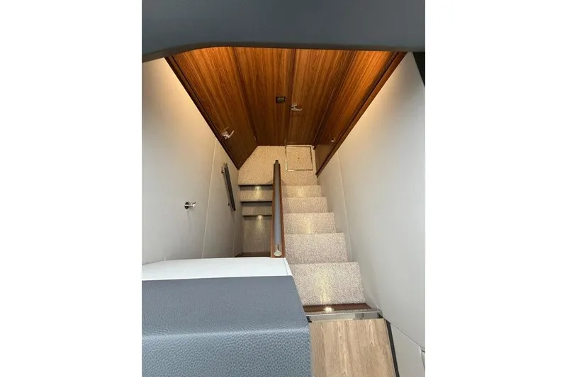  Yacht Photos Pics Interior staircase of 2023 Maritimo M600 yacht with wooden ceiling and carpeted steps.