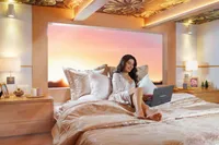 Woman relaxing on luxurious bed in Catamaran Ocean Beast 65, 2020 model, with sunset view.
