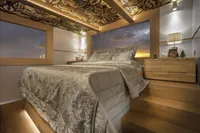 Luxurious bedroom on 2020 Catamaran Ocean Beast 65 with elegant decor and sunset view.