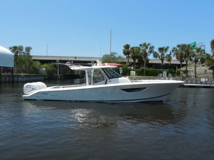 Fiji Kai Yacht Photos Pics 2023 Pursuit S378 boat on calm water, surrounded by trees and a bridge.