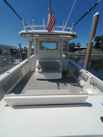 Fiji Kai Yacht Photos Pics 2023 Pursuit S378 boat with spacious deck and American flag, docked under clear blue sky.
