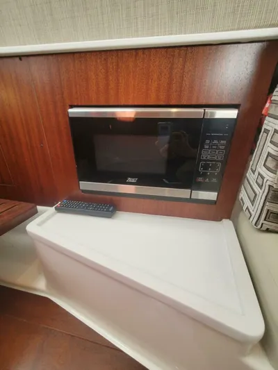 Fiji Kai Yacht Photos Pics 2023 Pursuit S378 interior with built-in microwave and remote control on a wooden panel.