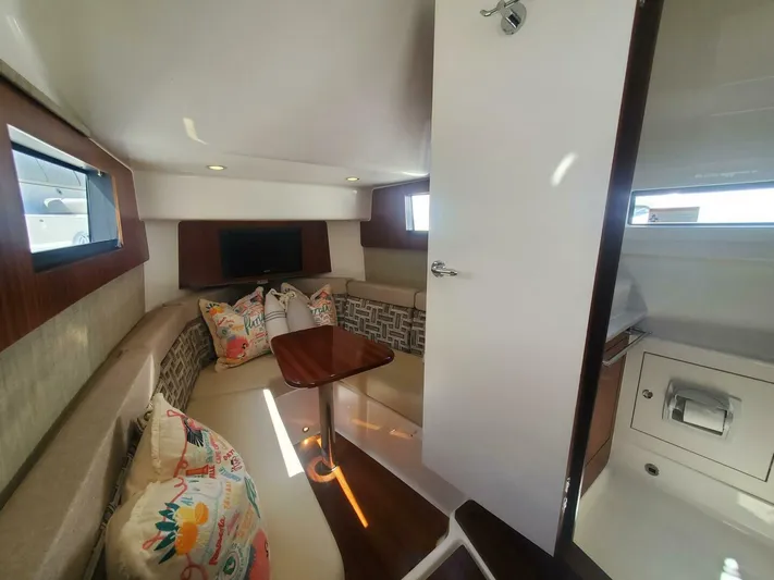 Fiji Kai Yacht Photos Pics 2023 Pursuit S378 cabin interior with cozy seating, decorative pillows, and a small table.
