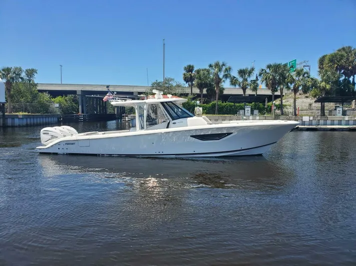 Fiji Kai Yacht Photos Pics 2023 Pursuit S378 boat cruising on a sunny day near a bridge and palm trees.