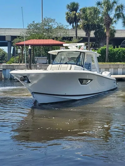 Fiji Kai Yacht Photos Pics 2023 Pursuit S378 boat on water near dock, surrounded by palm trees and blue sky.