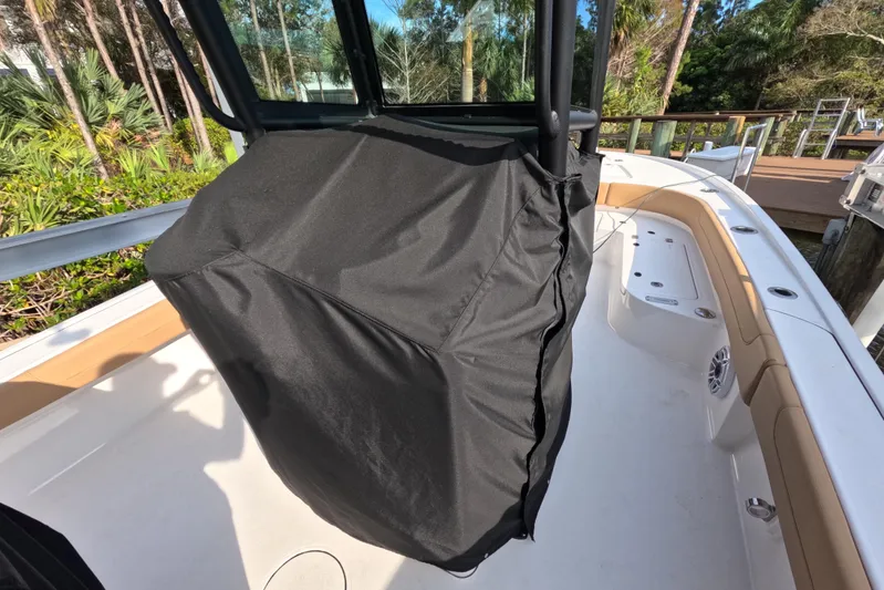  Yacht Photos Pics 2024 Caymas 281 HB boat interior with covered console, docked near lush greenery.