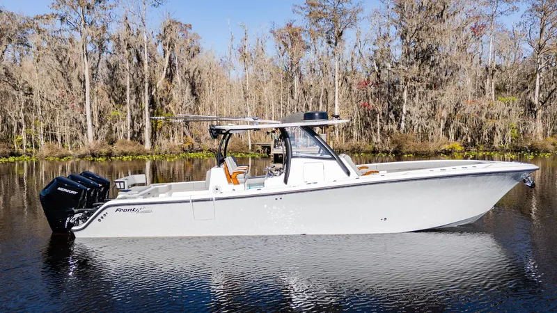  Yacht Photos Pics 2026 Front Runner 36 Center Console boat on calm water, surrounded by trees.