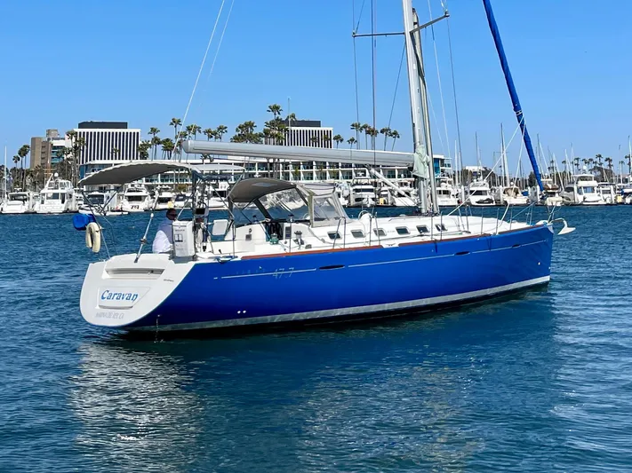 Caravan Yacht Photos Pics 2002 Beneteau First 47.7 sailboat in marina, blue hull, clear sky, waterfront buildings.