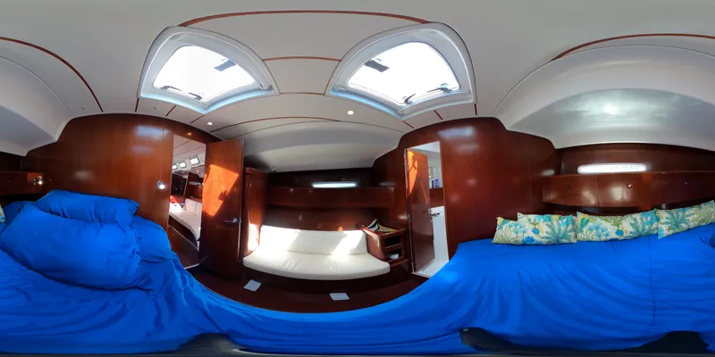 Caravan Yacht Photos Pics Interior of 2002 Beneteau First 47.7 yacht, featuring cozy wooden cabin and blue bedding.