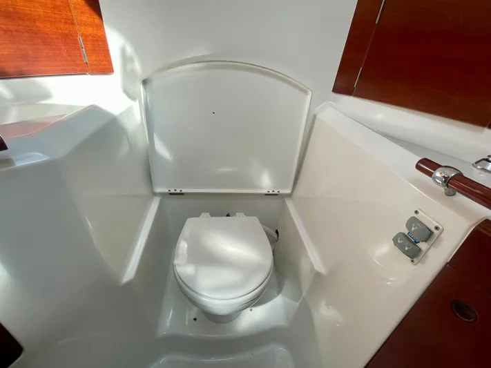 Caravan Yacht Photos Pics Beneteau First 47.7 2002 yacht bathroom with white toilet and wooden accents.