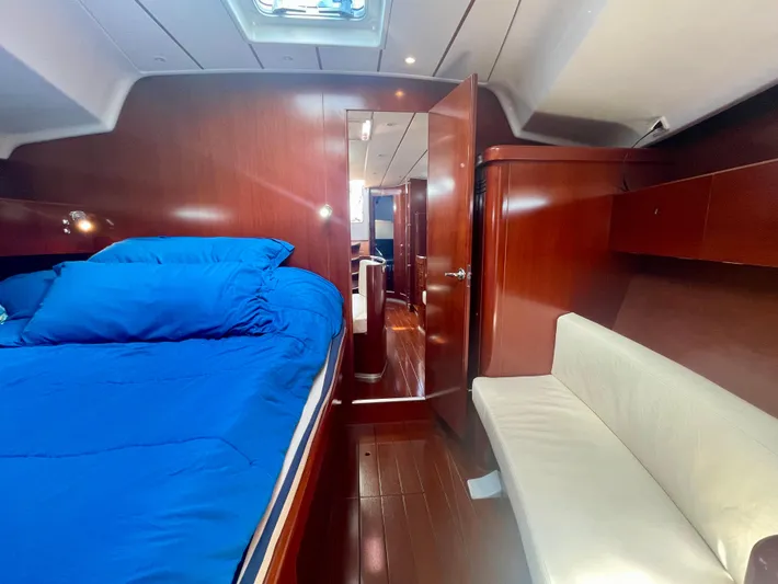 Caravan Yacht Photos Pics Luxurious cabin interior of 2002 Beneteau First 47.7 yacht with blue bedding and wooden finish.