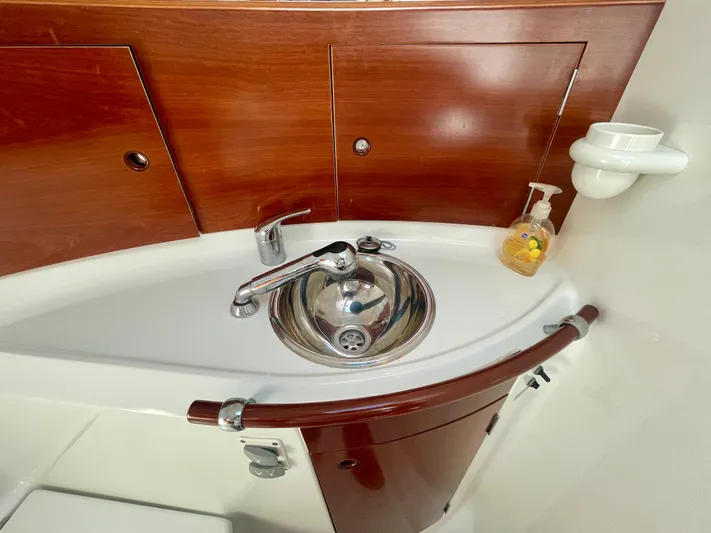 Caravan Yacht Photos Pics Beneteau First 47.7 2002 yacht bathroom sink with wooden cabinetry and soap dispenser.