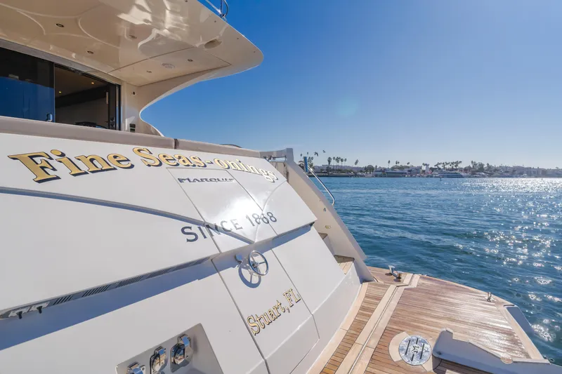 Fine Seas-onings Yacht Photos Pics Luxury Marquis 720 Fly yacht, 2018 model, docked by the ocean under clear blue skies.