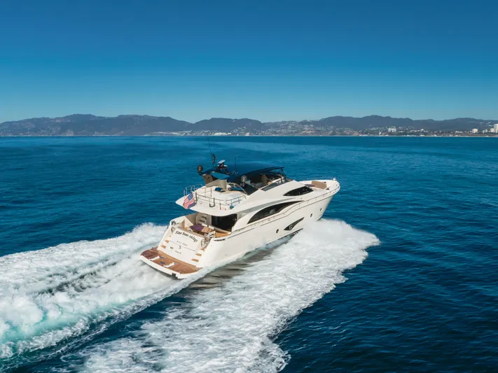 Fine Seas-onings Yacht Photos Pics Luxury 2018 Marquis 720 Fly yacht cruising on open sea with scenic mountain backdrop.