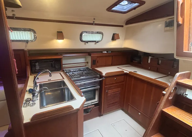 Blue Sky Yacht Photos Pics 2001 Island Packet 380 yacht kitchen with wooden cabinetry, stainless steel sink, and stove.