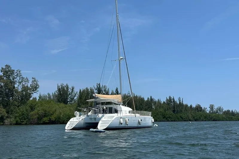 Alice Yacht Photos Pics 2015 Lagoon 380 S2 catamaran anchored on a serene waterway with lush greenery.