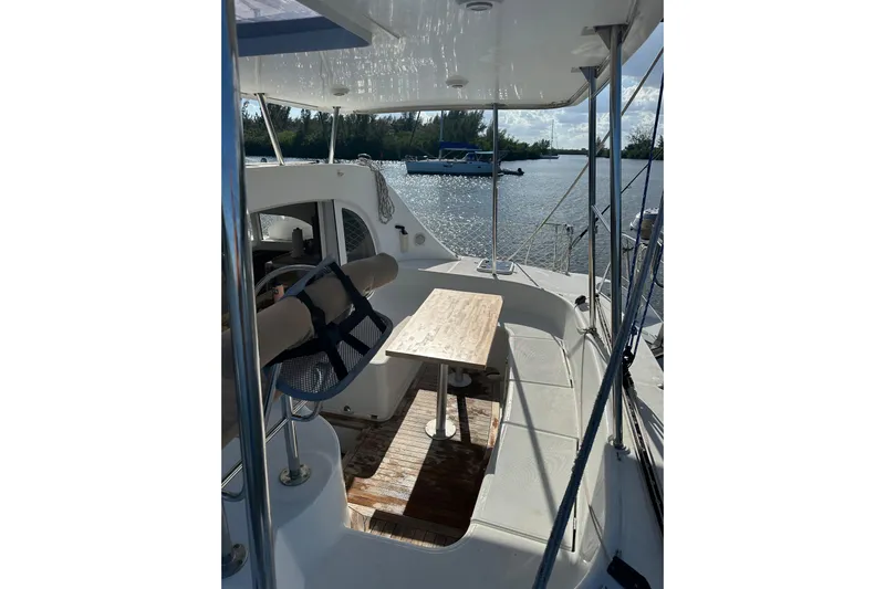 Alice Yacht Photos Pics 2015 Lagoon 380 S2 catamaran cockpit with table, steering wheel, and scenic water view.