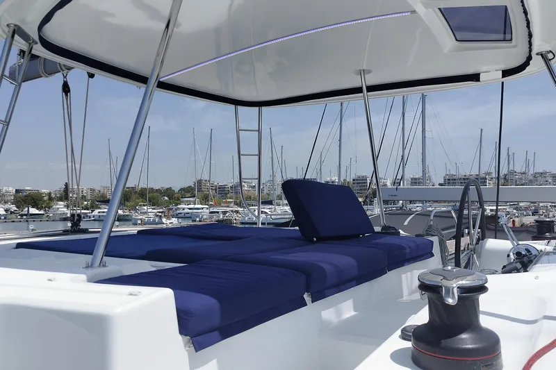  Yacht Photos Pics 2021 Lagoon 46 catamaran with blue seating, docked in a marina under clear skies.