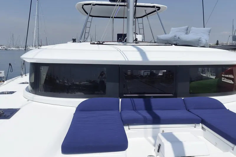  Yacht Photos Pics 2021 Lagoon 46 catamaran with blue cushions, docked at a marina.
