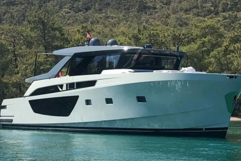  Yacht Photos Pics Luxury Bluegame BGX 70 yacht from 2020 on serene water, surrounded by lush greenery.