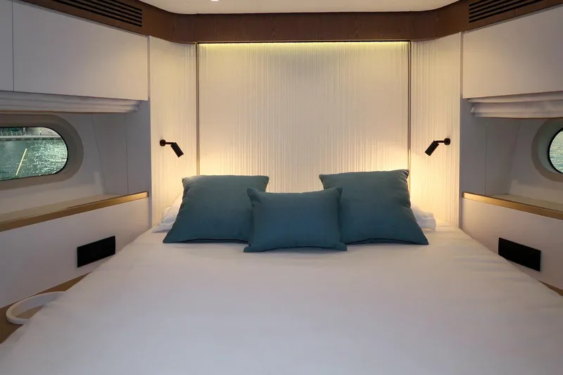 Azimut Magellano 60 Model 2025 Yacht Photos Pics Luxurious bedroom interior of 2025 Azimut Magellano 60 yacht with elegant lighting and blue pillows.