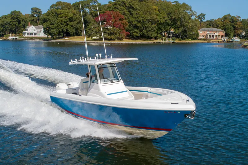 Ami Kids Donation Yacht Photos Pics 2015 Intrepid 327 Center Console boat cruising on a scenic lake.