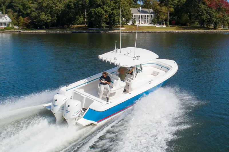 Ami Kids Donation Yacht Photos Pics 2015 Intrepid 327 Center Console boat cruising on a serene lake.