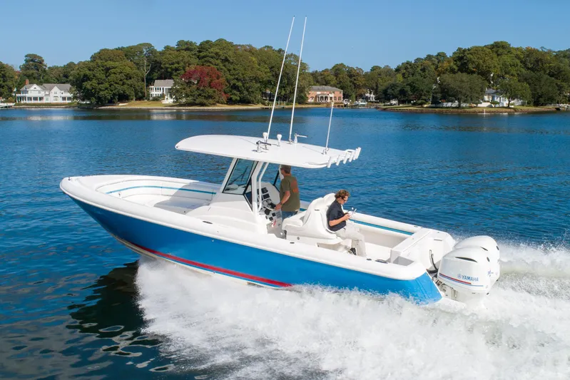 Ami Kids Donation Yacht Photos Pics 2015 Intrepid 327 Center Console boat cruising on a serene lake.