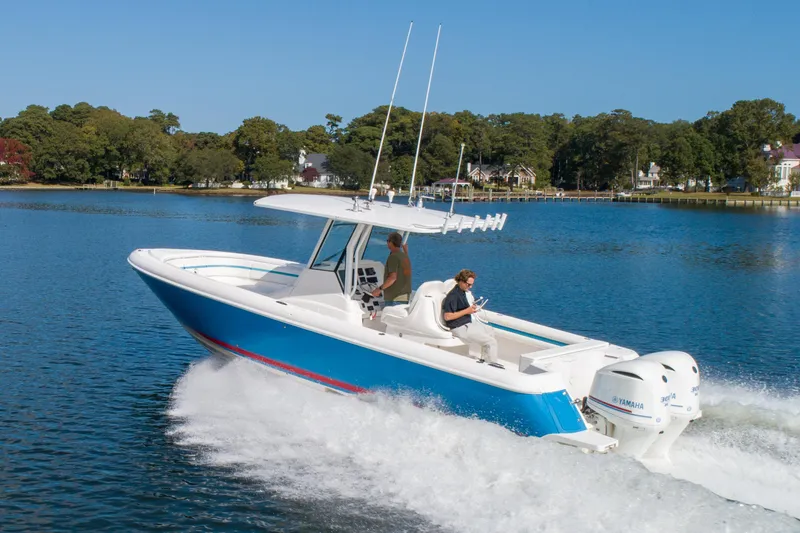 Ami Kids Donation Yacht Photos Pics 2015 Intrepid 327 Center Console boat cruising on a scenic lake.