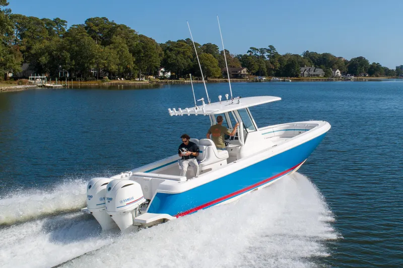 Ami Kids Donation Yacht Photos Pics 2015 Intrepid 327 Center Console boat cruising on a scenic lake.