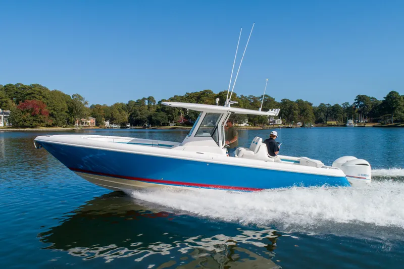 Ami Kids Donation Yacht Photos Pics 2015 Intrepid 327 Center Console boat cruising on a serene lake.