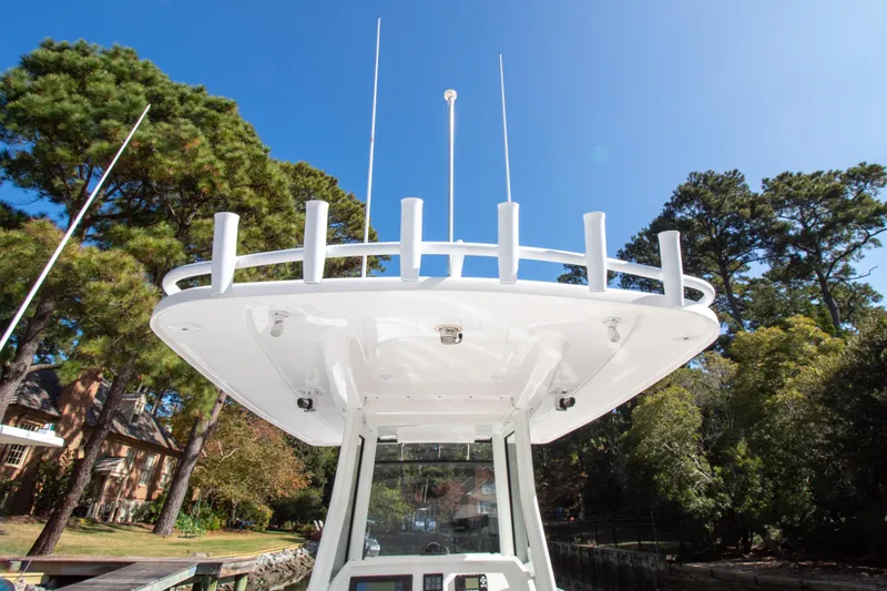 Ami Kids Donation Yacht Photos Pics 2015 Intrepid 327 Center Console boat with rod holders, surrounded by trees.