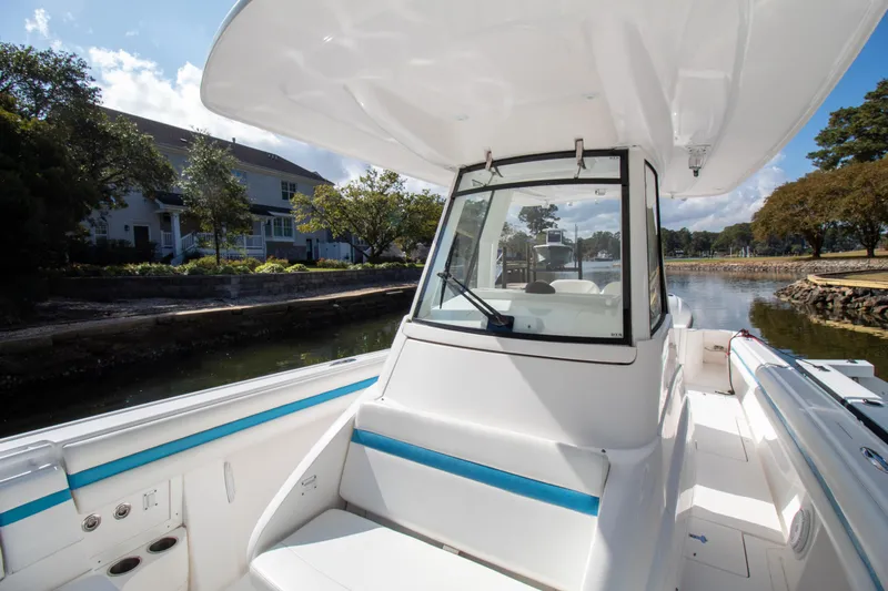 Ami Kids Donation Yacht Photos Pics 2015 Intrepid 327 Center Console boat on a calm waterway, showcasing sleek design.