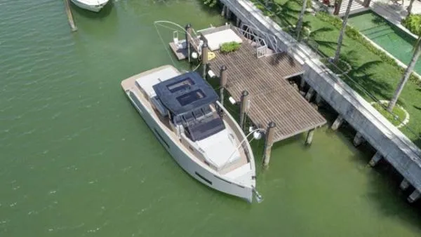  Yacht Photos Pics 2022 De Antonio Yachts D42 docked by a wooden pier in a serene marina.