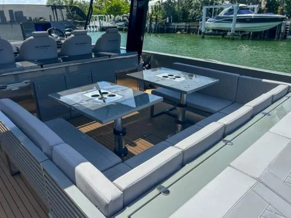  Yacht Photos Pics 2022 De Antonio Yachts D42 interior with seating and tables, docked by the water.