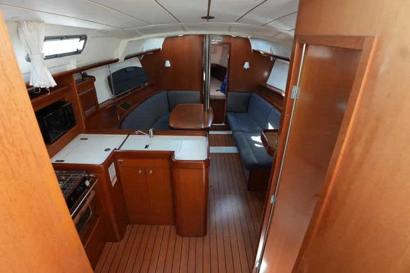 Andiamo! Yacht Photos Pics Interior of 2007 Beneteau 373 sailboat with wood finish and cozy seating area.