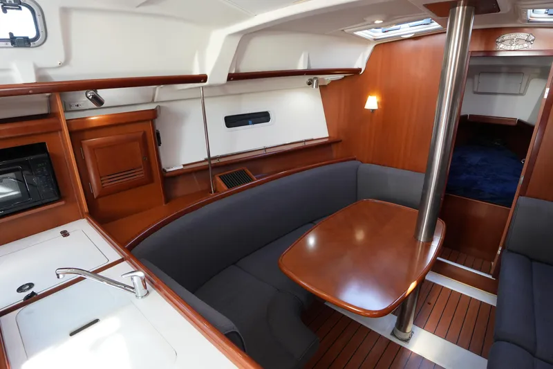Andiamo! Yacht Photos Pics Interior of 2007 Beneteau 373 sailboat with wood finish and cozy seating area.