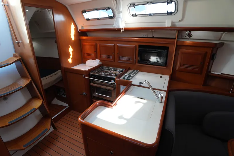 Andiamo! Yacht Photos Pics Interior of 2007 Beneteau 373 sailboat with kitchen and wooden cabinetry.