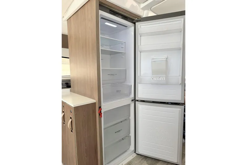 High School Yacht Photos Pics Modern Bali 4.2 refrigerator, 2023 model, open with spacious interior and wooden paneling.