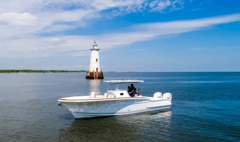  Yacht Photos Pics 2025 Buddy Davis 34 Center Console boat near a lighthouse on a sunny day.