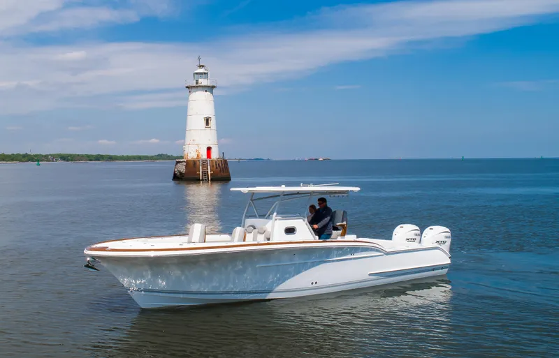  Yacht Photos Pics 2025 Buddy Davis 34 Center Console boat near a lighthouse on calm waters.