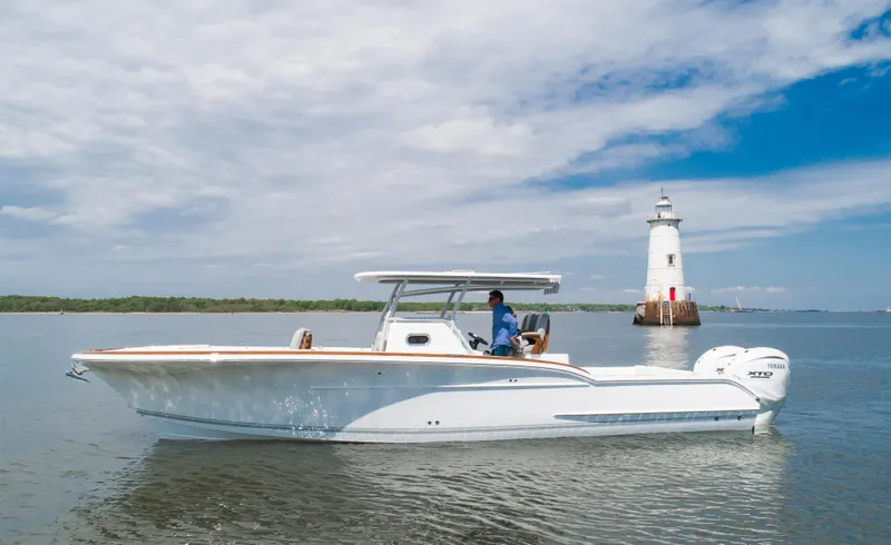  Yacht Photos Pics 2025 Buddy Davis 34 Center Console boat near a lighthouse on calm water.
