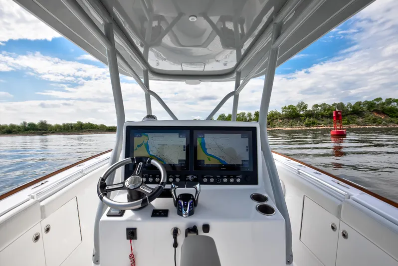  Yacht Photos Pics 2025 Buddy Davis 34 Center Console boat dashboard with dual navigation screens on a calm waterway.