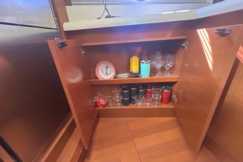  Yacht Photos Pics Open cabinet on Beneteau Gran Turismo 44 yacht, displaying glasses and nautical-themed plates.