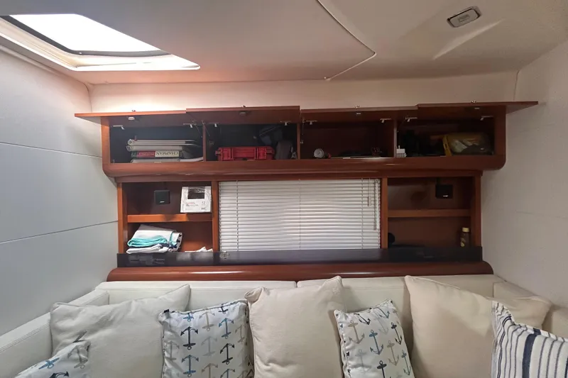  Yacht Photos Pics Interior of 2012 Beneteau Gran Turismo 44 with wooden shelves and nautical-themed cushions.