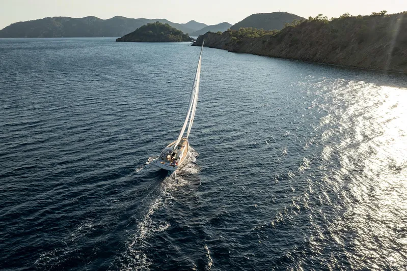 Hanse 588 Yacht Photos Pics Sailing yacht Hanse 588 (2024) navigating scenic coastal waters with mountainous backdrop.