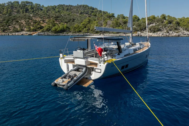 Hanse 588 Yacht Photos Pics 2024 Hanse 588 yacht anchored in serene blue waters, surrounded by lush greenery.