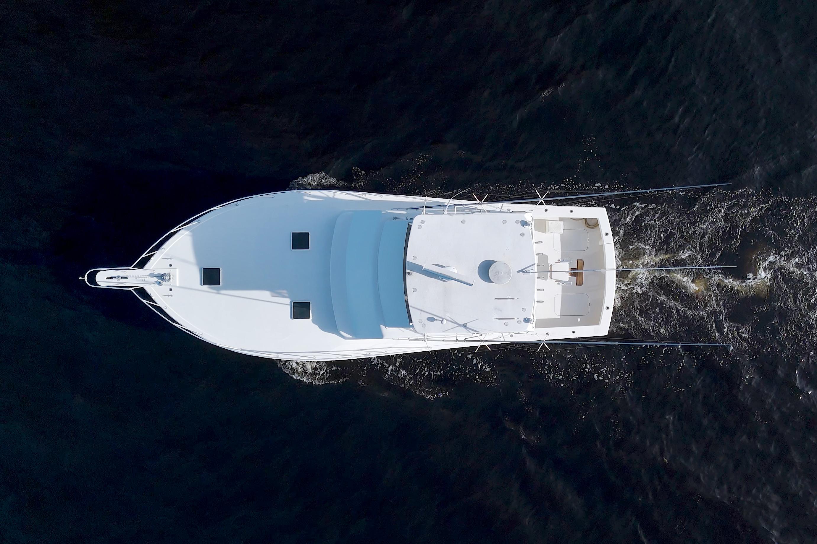 Aerial view of 1990 Post 44 Sport Fisherman boat cruising on dark water.
